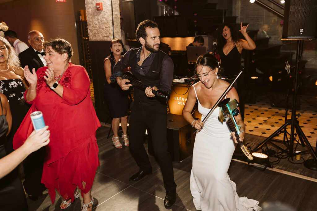 Live violinist and DJ performing during a high-energy wedding reception