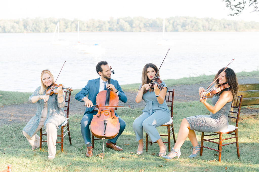 Elegance quartet team performing outdoors by the water at a wedding ceremony